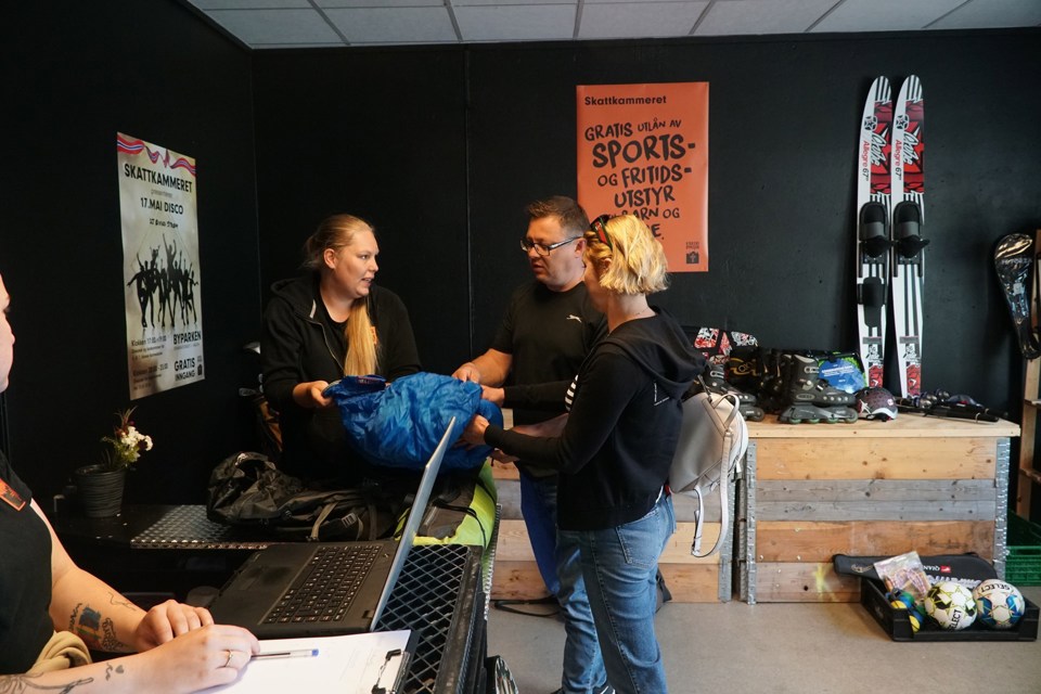 Tre mennesker som snakker sammen. I bakgrunn er det diverse sportsutstyr.