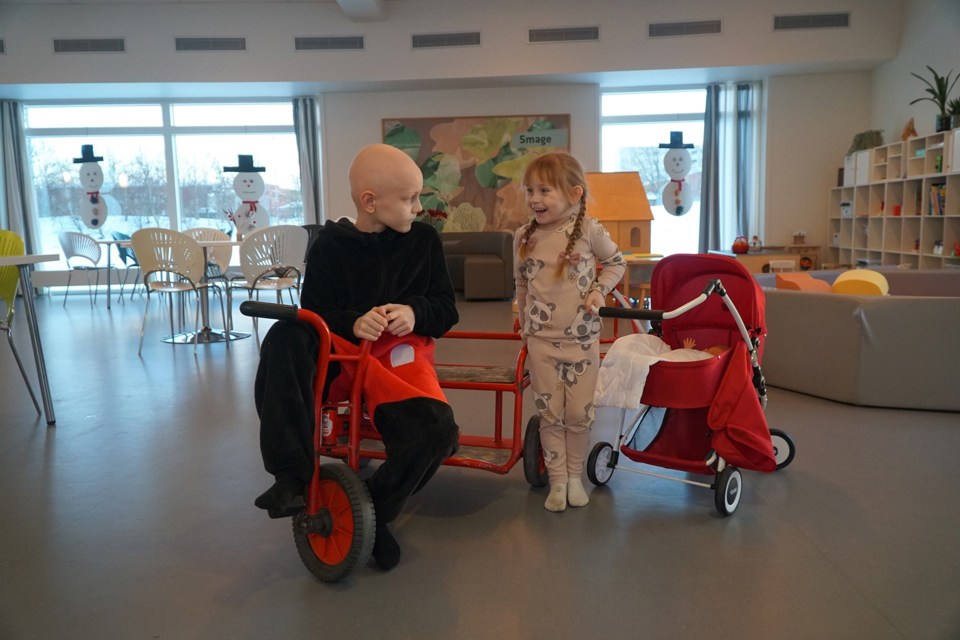 Elvira leker med broren Thor. Elvira har en rød dukkevogn, og Thor i Mikke Mus-drakt på en rød sykkel.