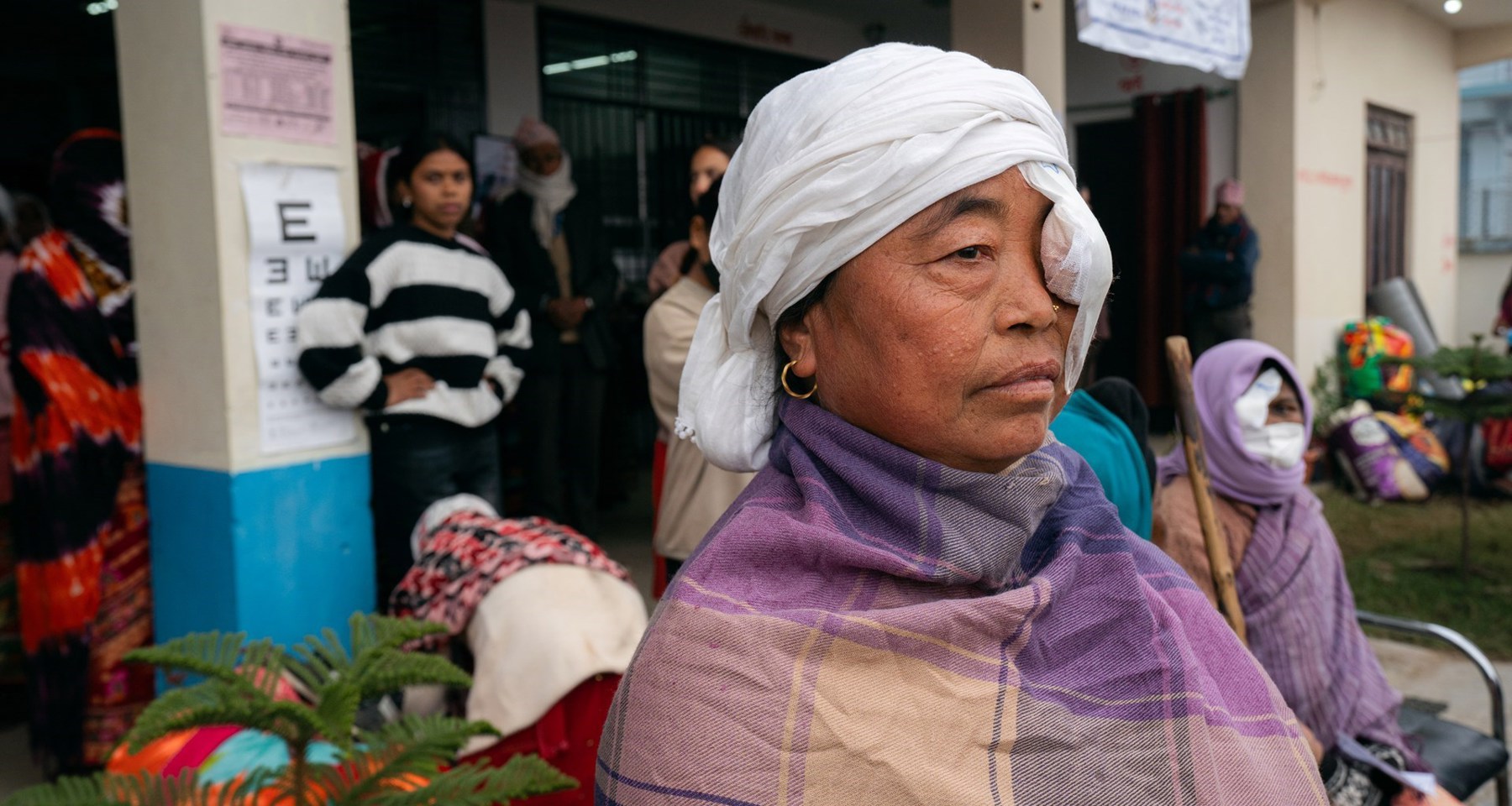 Kvinne i Nepal sitter med lapp foran øyet ved øyeklinikk. 